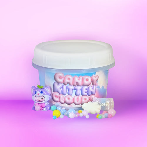 A clear plastic tub with a white lid labeled 'Candy Kitten Cloud' in pastel pink and blue lettering, shown on a pink-to-purple gradient background. A small purple cartoon kitten figure, pastel beads, and a white cloud-shaped accessory are arranged around the tub.
