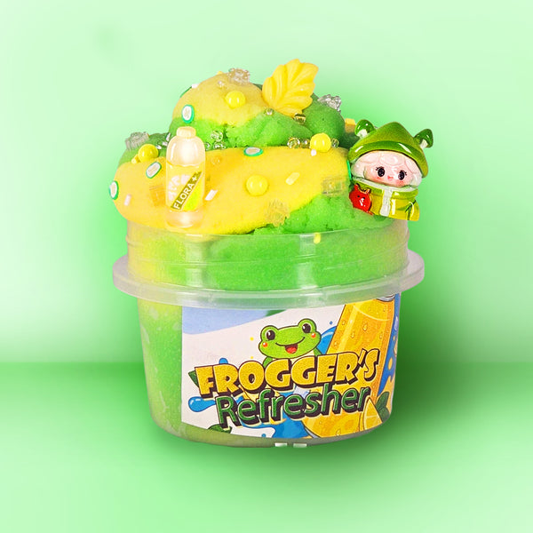 A tub of green slime topped with yellow slime, decorative leaf pieces, small bubbles, and a small frog-themed character figure, labeled 'FROGGER'S Refresher' on a light green background.